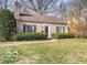 Cottage-style home with a stone facade, a red front door, manicured bushes, and mature trees at 6030 Evanston Ave, Indianapolis, IN 46220