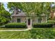 A charming stone home with a red front door, well-maintained landscaping, and mature trees at 6030 Evanston Ave, Indianapolis, IN 46220