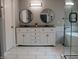 Modern bathroom with double vanity, round mirrors, granite countertops, and a glass enclosed shower at 6483 Timber Walk Dr, Indianapolis, IN 46236