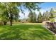 Spacious, well-manicured backyard featuring lush green grass and mature trees, with a dining set at 8201 Castle Dr, Indianapolis, IN 46256
