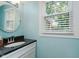 Bright bathroom featuring a vanity with granite countertop and a round mirror at 8201 Castle Dr, Indianapolis, IN 46256