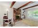 Cozy living room with exposed wood beams, a brick fireplace, and bright windows at 8201 Castle Dr, Indianapolis, IN 46256
