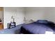 A well-lit bedroom with blue carpet, a bed, a table with a lamp, and an open doorway at 8778 N Deer Crossing Blvd, McCordsville, IN 46055