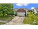 A well-maintained home featuring a two-car garage, long driveway, and mature landscaping at 8778 N Deer Crossing Blvd, McCordsville, IN 46055