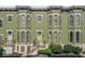 A close-up of the green painted townhomes showing the bay windows and the yellow painted front doors at 914 N Alabama St, Indianapolis, IN 46202