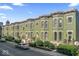 Row of green painted townhomes with bay windows, black iron fences, and manicured landscaping at 914 N Alabama St, Indianapolis, IN 46202