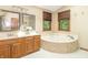 Bathroom with double vanity, wooden cabinets, and a tiled soaking tub at 10518 Courageous Dr, Indianapolis, IN 46236