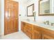 Bathroom with double sinks, warm wooden cabinets, and a neutral tile floor at 10518 Courageous Dr, Indianapolis, IN 46236