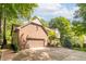 Brick home showcasing a multi-car garage and driveway surrounded by mature trees at 10518 Courageous Dr, Indianapolis, IN 46236