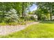 Manicured front yard featuring a stone retaining wall, mature trees, and tiered landscaping at 10518 Courageous Dr, Indianapolis, IN 46236