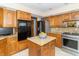 Well-equipped kitchen with oak cabinets, stainless steel appliances, and a granite-topped kitchen island at 10518 Courageous Dr, Indianapolis, IN 46236