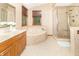 Elegant main bathroom featuring a soaking tub, tiled shower, and wooden cabinets at 10518 Courageous Dr, Indianapolis, IN 46236