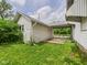 An exterior shot showing a white house with a covered parking area and overgrown yard at 1201 Arrow Ave, Anderson, IN 46016