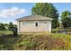 Garage exterior featuring a white door and trim, set against a backdrop of lush greenery and a blue sky at 1430 W 14Th St, Anderson, IN 46016
