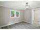 A living room with wood floors is lit by a hanging light fixture and sunlit by two windows at 1430 W 14Th St, Anderson, IN 46016