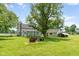 Exterior backyard view featuring a white home, garage, and fire pit on a well-manicured green lawn at 16000 W 700 S, Anderson, IN 46017