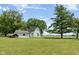 Exterior view of a white home and garage on a large green lawn, with hay bales in the distance at 16000 W 700 S, Anderson, IN 46017