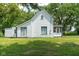 Rear exterior view of a white home featuring sliding doors, a small porch, and lush green lawn at 16000 W 700 S, Anderson, IN 46017
