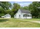 Quaint white home with a sunroom and detached garage on a meticulously maintained green lawn at 16000 W 700 S, Anderson, IN 46017