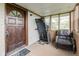 Enclosed front porch featuring a vintage door, comfortable chair, and large windows at 16000 W 700 S, Anderson, IN 46017
