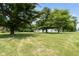 Sprawling green lawn with mature trees offering a picturesque view of the house and garage at 16000 W 700 S, Anderson, IN 46017