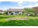 Spacious backyard with green lawn, garden bed, mature landscaping, and a view of the home's exterior at 2402 Redspire Blvd, Goshen, IN 46526