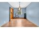 Light-filled dining room featuring wood flooring, a modern light fixture, and blue-grey walls with views of the yard at 2823 Tulip Dr, Indianapolis, IN 46227