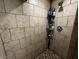 Corner tiled shower with multiple shelves holding various shampoos and soaps at 3054 Ruckle St, Indianapolis, IN 46205