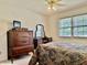Bedroom featuring dark wood furniture, dresser with mirror, fan, and window at 3418 S Rosewind Dr, New Palestine, IN 46163