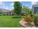 Backyard with green grass, pergola-covered seating area, hot tub, shed, and landscaped flower bed at 3420 Stoddard Pl, Indianapolis, IN 46217