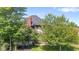 Lush backyard view with mature trees partially obscuring the home's exterior and a brick chimney at 4465 W Woodbridge Ln, New Palestine, IN 46163