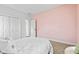 Cozy bedroom with white comforter, pale pink accent wall, and view of backyard at 4465 W Woodbridge Ln, New Palestine, IN 46163
