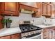 Modern stove top and sink in kitchen with marble countertops and wood cabinets at 4465 W Woodbridge Ln, New Palestine, IN 46163