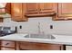 Close-up of a kitchen sink, stovetop, marble countertop, and wooden cabinetry at 4465 W Woodbridge Ln, New Palestine, IN 46163