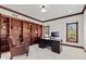 This is a home office with custom built-in shelving, large window and leather chair at 4465 W Woodbridge Ln, New Palestine, IN 46163