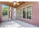 Exterior screened-in porch with red brick facade, ceiling fan, and access to both the house and backyard at 4465 W Woodbridge Ln, New Palestine, IN 46163