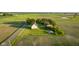 Aerial view of a quaint, multi-building farmstead surrounded by expansive green farmland on a sunny day at 6012 N 200 W, Greenfield, IN 46140