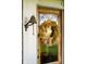 A weathered farm bell hanging outside a door decorated with a dried floral wreath and glass pane at 6012 N 200 W, Greenfield, IN 46140