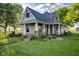 Charming home featuring a covered porch, inviting garden, and lush green lawn, set against a blue sky at 6012 N 200 W, Greenfield, IN 46140