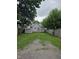 Backyard with mature trees, shed, gravel drive, and partially fenced yard at 624 Warren Ave, Indianapolis, IN 46221