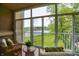 Screened porch with comfortable wicker furniture overlooking lush green lawn and pond at 6640 Page Blvd # 101, Indianapolis, IN 46220