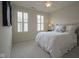 Cozy bedroom with neutral carpet, white bedding, shutters, and a bedside table illuminated by a table lamp at 692 Greenford N Trl, Carmel, IN 46032