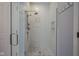 Modern shower featuring marble-like tiles, glass door and panels, a shower niche, and brushed nickel fixtures at 692 Greenford N Trl, Carmel, IN 46032