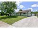 Inviting home with green siding, manicured lawn, and gravel driveway leading to a detached garage at 710 S Bancroft St, Indianapolis, IN 46203
