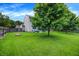 Spacious backyard with a lush lawn, mature trees, a patio set, and wooden fencing at 7215 Braxton Dr, Noblesville, IN 46062