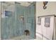 Beautiful blue tiled shower with glass door, stone flooring, and recessed shelving at 7215 Braxton Dr, Noblesville, IN 46062