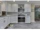 Kitchen features white cabinets, stainless steel appliances, mosaic backsplash, and modern gray wood flooring at 784 S Restin Rd, Greenwood, IN 46142