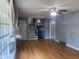 Living room with hardwood floors, ceiling fan, gray walls, large window with light curtains, and stairs at 8008 Cherington Dr, Indianapolis, IN 46227