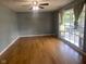 Living room with hardwood floors, ceiling fan, gray walls, and large window with light curtains at 8008 Cherington Dr, Indianapolis, IN 46227