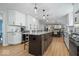 Spacious kitchen flows to dining, boasting white cabinets, a central island with seating, and hardwood floors at 8827 Lindsey Ct, Fishers, IN 46038